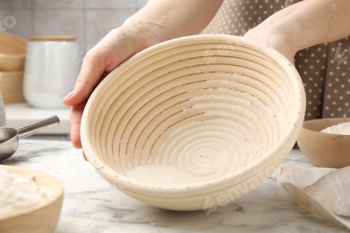 Preview: Woman with sourdough proofing basket at table, closeup