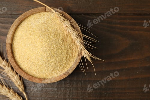Preview: Raw semolina in bowl and spikes on wooden table, flat lay. Space for text