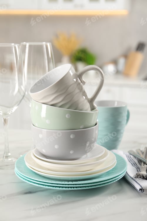 Preview: Many different clean dishware and cups on white marble table in kitchen