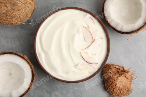 Preview: Delicious coconut yogurt with flakes in bowl and fruits on grey marble table, flat lay
