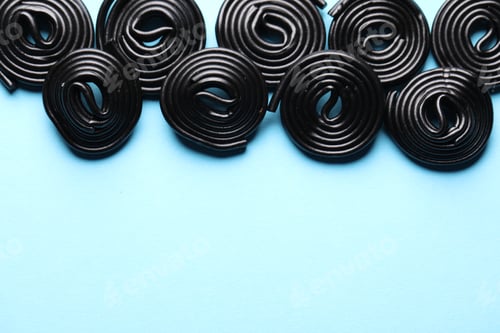 Preview: Natural licorice candies on light blue background, flat lay. Space for text