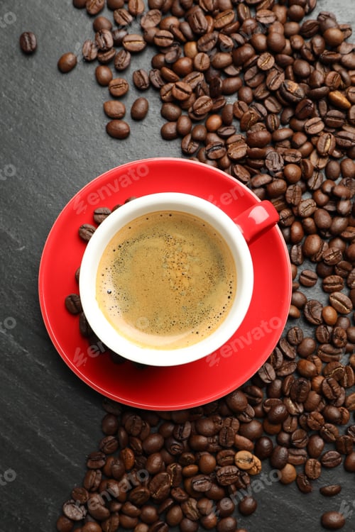 Preview: Cup with aromatic coffee and beans on dark textured table, flat lay
