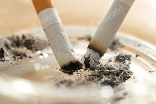 Preview: Cigarette butts smoldering in ashtray on table, closeup