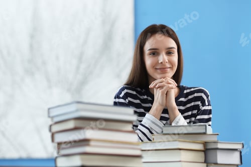 Preview: Young woman with stacks of colorful books at home