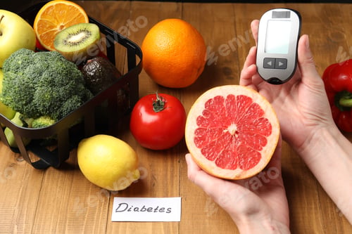 Preview: Diabetes. Woman with digital glucometer, grapefruit, other fruits and vegetables at wooden table, cl