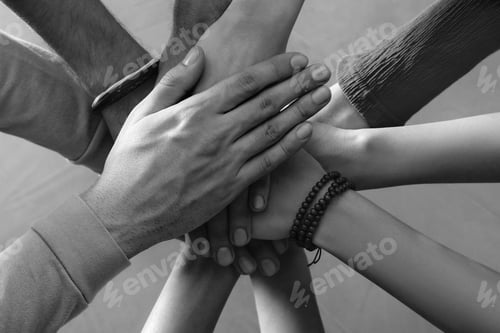 Preview: Group of people stacking their hands together, top view. Black-and-white toning