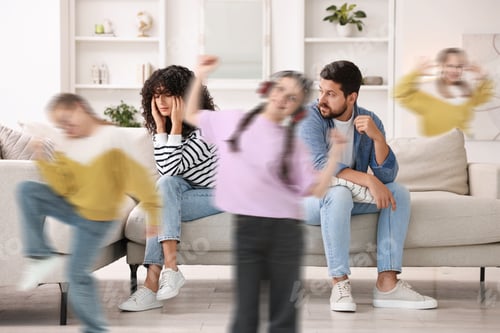 Preview: Family with hyperactive children. Kids having fun while tired parents sitting on sofa