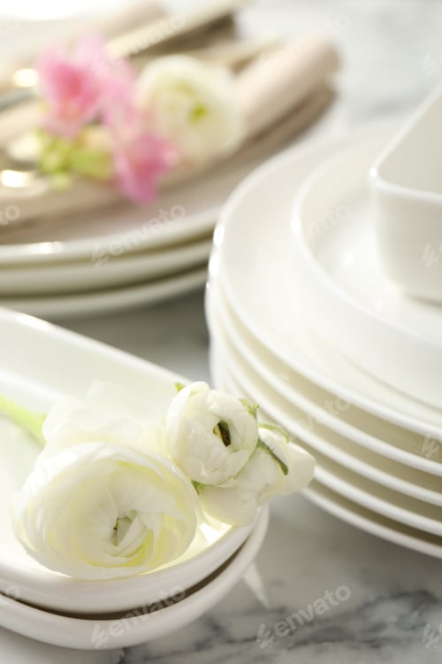 Preview: Many clean dishware and beautiful flowers on white marble table, closeup