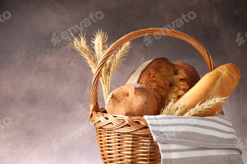 Preview: Different types of bread and spikes in wicker basket on grey background, closeup. Space for text