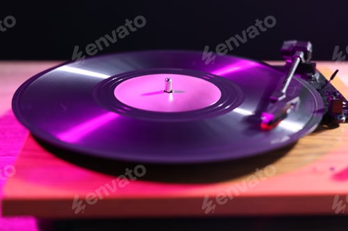 Preview: Modern turntable with vinyl record on table in color lights, closeup