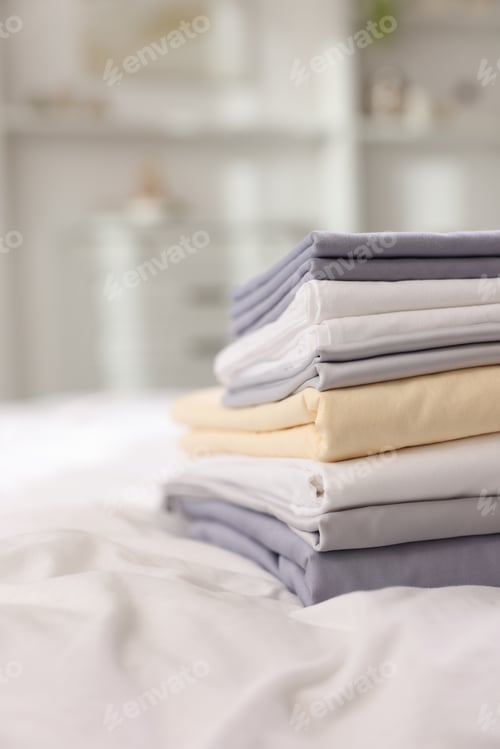 Preview: Stack of fresh linens on bed indoors, closeup. Space for text