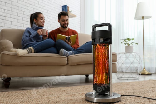 Preview: Couple on sofa in room with electric heater, selective focus