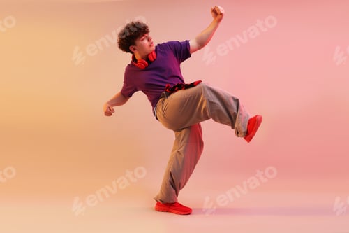 Preview: Young man performing hip-hop dance on color background