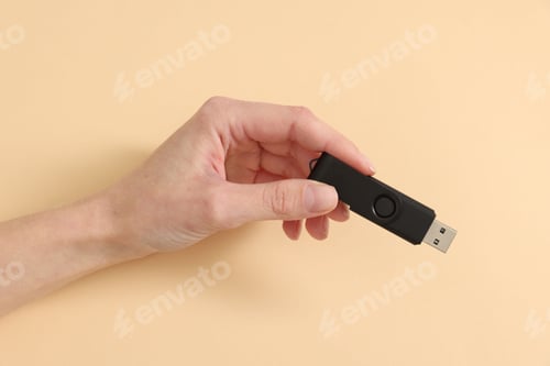 Preview: Woman with USB flash drive on beige background, closeup