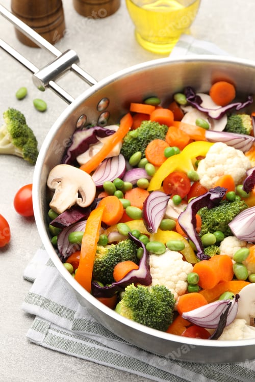 Preview: Uncooked mix of vegetables in frying pan on light grey table, closeup