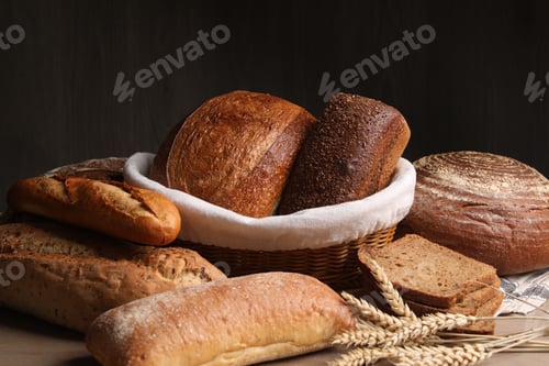 Preview: Different types of bread and wheat spikes on wooden table, closeup