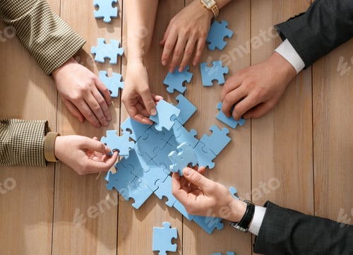 Preview: Team building. Group of businesspeople solving puzzle together at wooden table, top view