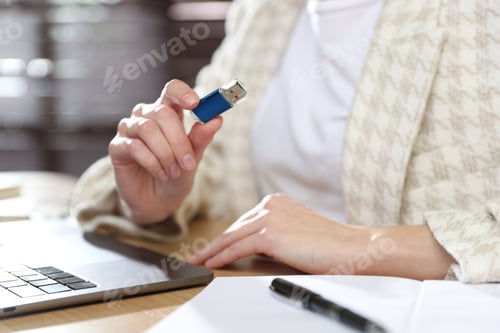Preview: Woman with USB flash drive at wooden desk, closeup