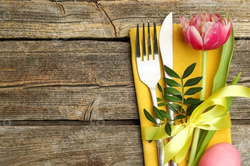 Preview: Easter table setting. Beautiful silverware with tulip and painted egg on wooden background, top view