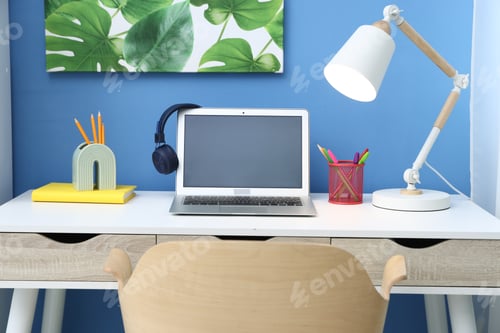 Preview: Stylish workplace with laptop, headphones and stationery in child's room