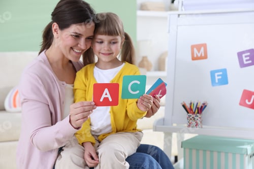 Preview: Mother teaching her daughter alphabet with letter cards at home