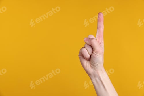 Preview: Woman pointing upwards on yellow background, closeup. Space for text
