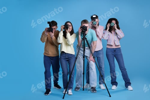 Preview: Group of photographers taking pictures with professional cameras against light blue background