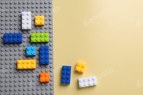 Preview: Construction toy. Colorful building blocks on yellow background, flat lay. Space for text