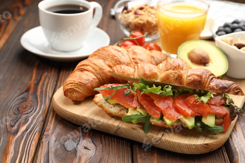 Preview: Healthy breakfast. Tasty croissants with salmon, avocado, oatmeal and drinks on wooden table, closeu