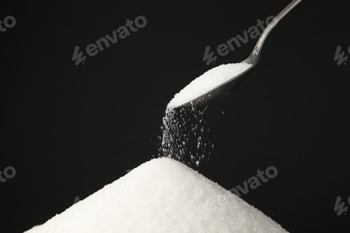 Preview: Pouring granulated sugar onto pile against black background, closeup