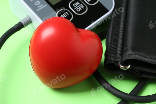 Preview: Measuring blood pressure. Sphygmomanometer and heart figure on light green background, closeup