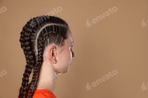 Preview: Teenage girl with beautiful braids on beige background. Space for text