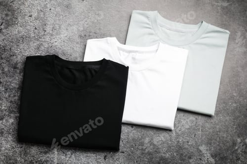 Preview: Blank folded t-shirts on grey textured background, top view. Mockup for design