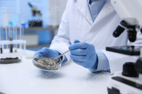 Preview: Laboratory testing. Scientist taking sample of sand for research at white table indoors, closeup