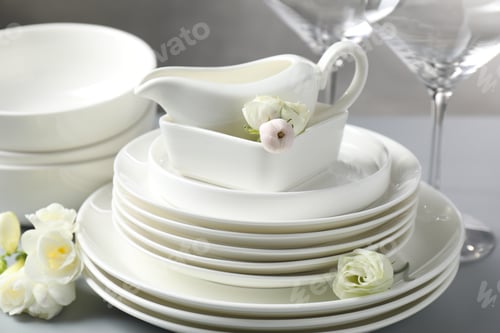 Preview: Many clean dishware and beautiful flowers on grey table, closeup