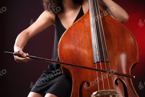 Preview: Woman playing double bass on dark red background, closeup