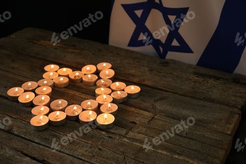 Preview: Holocaust Remembrance Day. Burning candles in shape of Star of David on wooden table and flag of Isr
