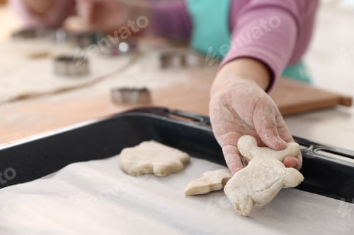 Preview: Grandmother and her granddaughter making cookies together at table in kitchen, closeup