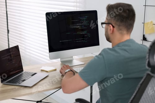 Preview: Young programmer working at desk in office