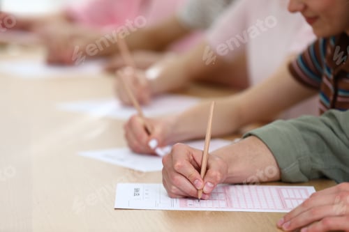 Preview: Students taking test at wooden desk in classroom, closeup