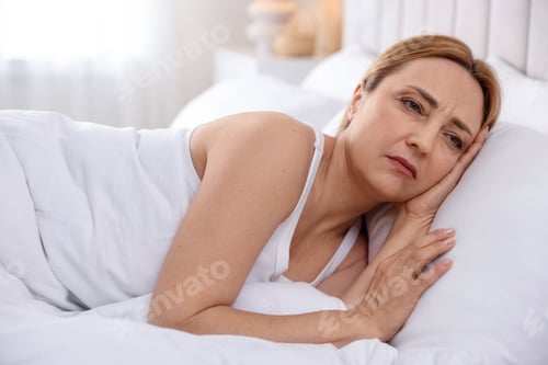Preview: Menopause. Upset woman lying in bed at home