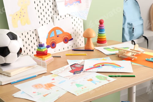 Preview: Stylish workplace with wooden table, stationery, toys and drawings near green wall in child's room,