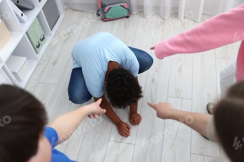 Preview: African American boy getting bullied by his classmates in classroom, above view