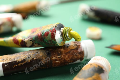Preview: Tubes with watercolor paints on green background, closeup