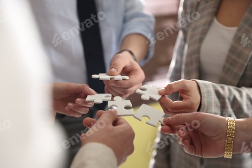 Preview: Team building. Group of businesspeople putting puzzle pieces together indoors, closeup
