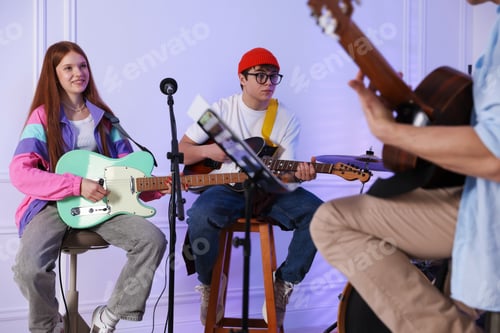 Preview: Teenage band practicing their performance with music teacher indoors