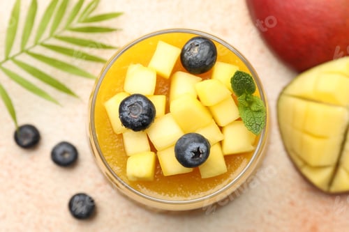 Preview: Delicious mango panna cotta with fruits and mint in glass on beige table, flat lay