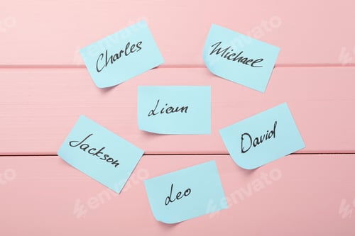 Preview: Paper stickers with different names on pink wooden background, flat lay. Choosing baby's name