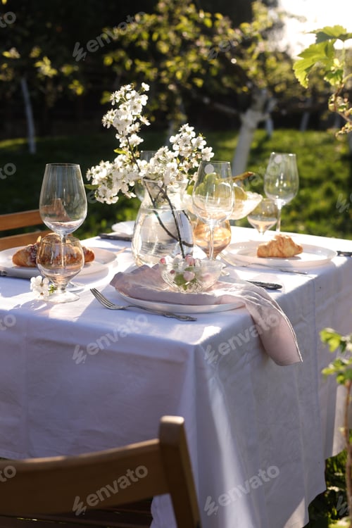 Preview: Beautiful table setting with spring flowers in garden on sunny day