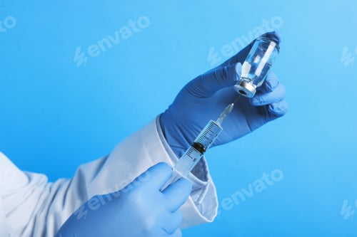 Preview: Vaccination. Medical worker filling syringe with medication on light blue background, closeup